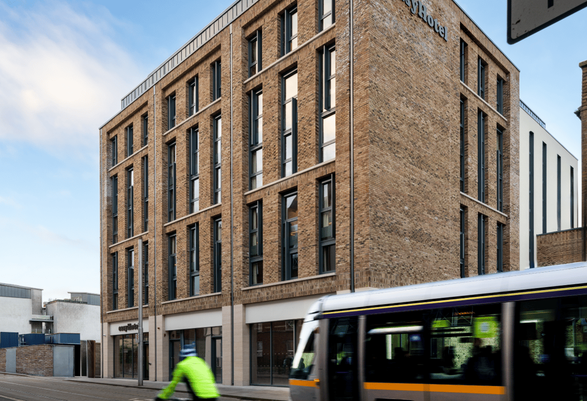 Modern brick easyHotel building exterior in Dublin, on a city street with a tram and cyclist in the foreground.