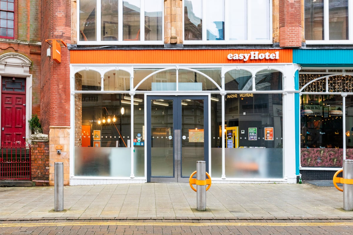 easyHotel Birmingham hotel exterior, showcasing its orange facade, large glass windows, and main entrance on a city street.