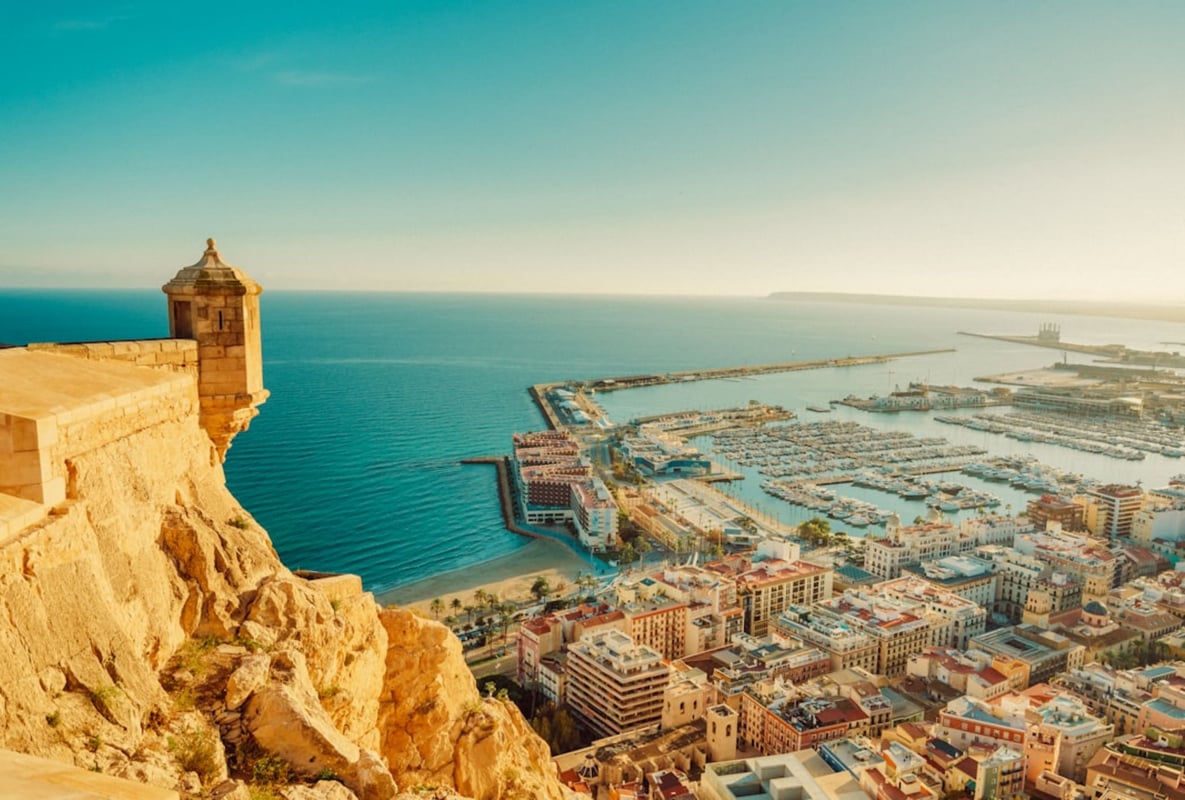 An image of the port in Alicante, with blue skies and a view of the entire city, taken from above.