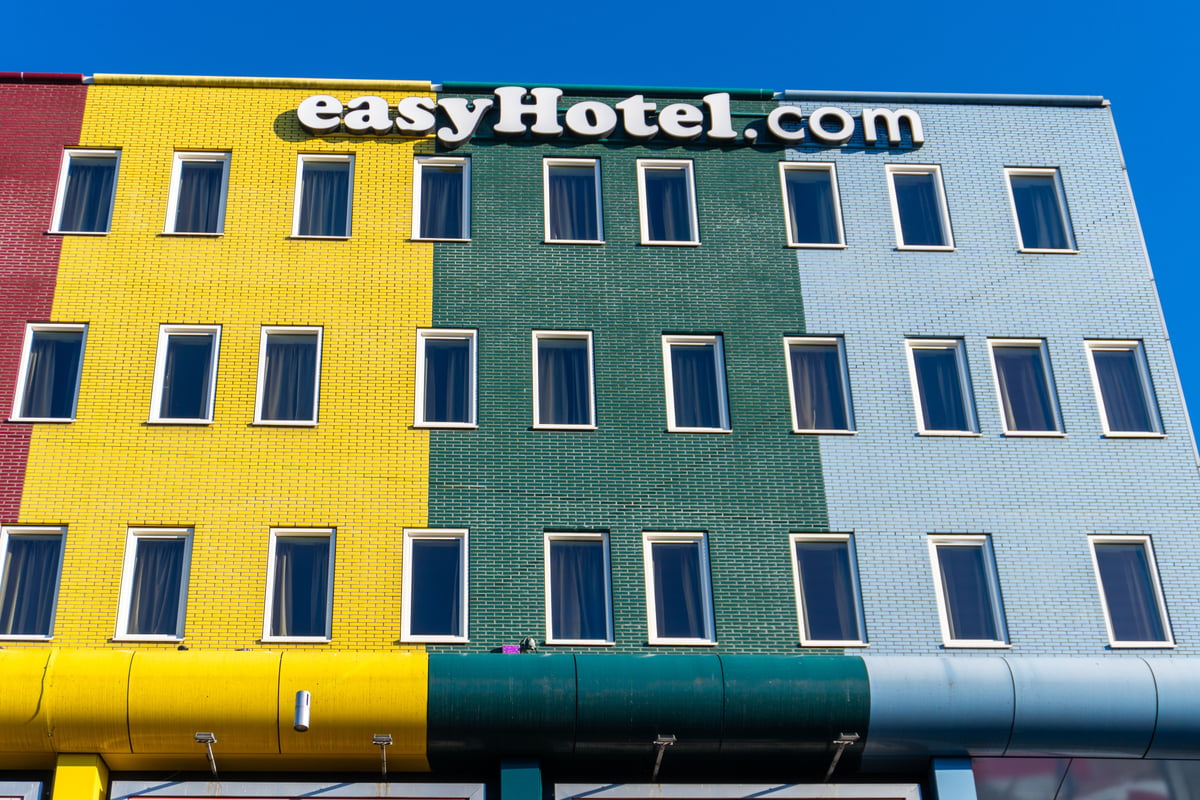 easyHotel Amsterdam Arena exterior with a vibrant, multicolored facade in red, yellow, green, and light blue brickwork, under a clear blue sky.