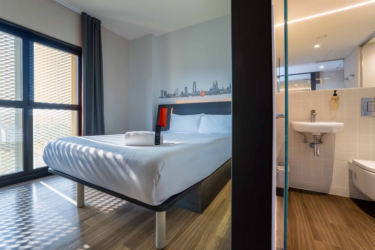 EasyHotel Barcelona Fira double room with a double bed, white linens, and a cityscape mural above the headboard.