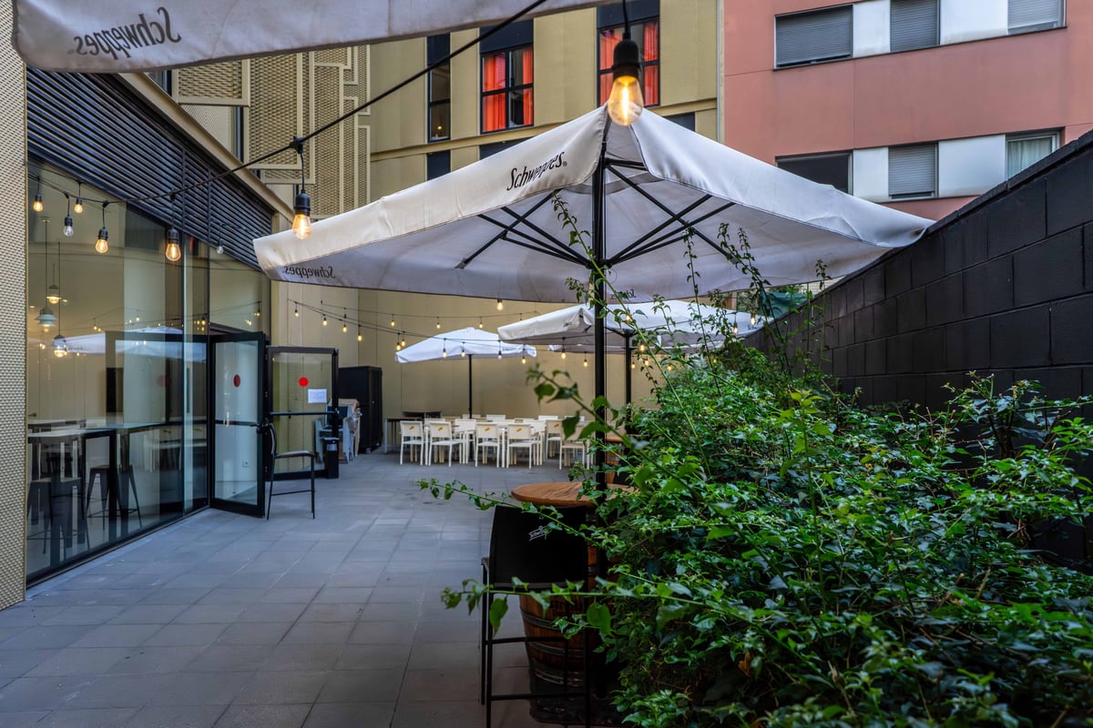 Outdoor seating area at easyHotel Barcelona Fira with tables and chairs under white umbrellas.