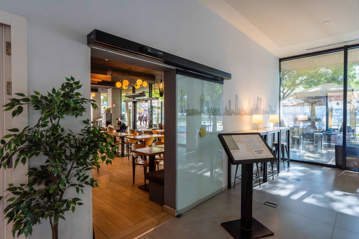 EasyHotel Barcelona Fira reception area with a view into the dining area featuring tables and chairs.