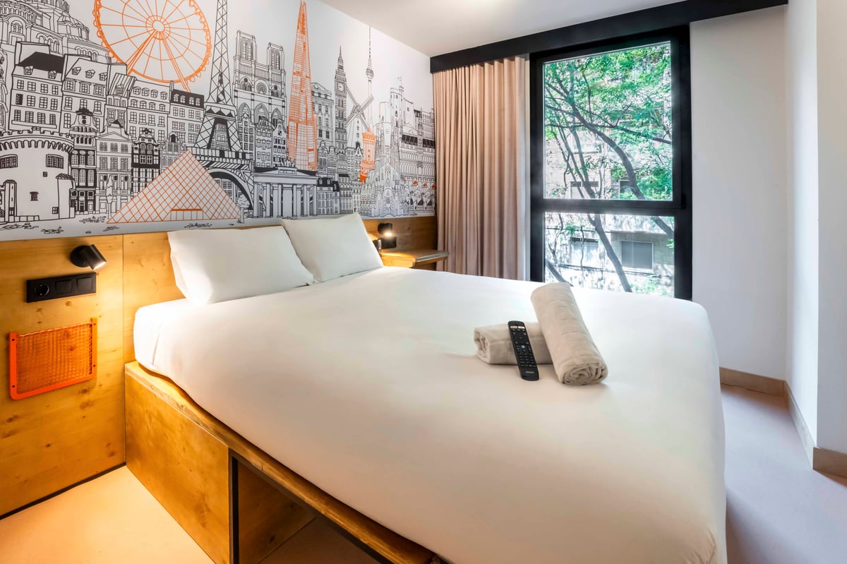 EasyHotel Barcelona La Sagrera double room with white bedding, pillows, and a window view.