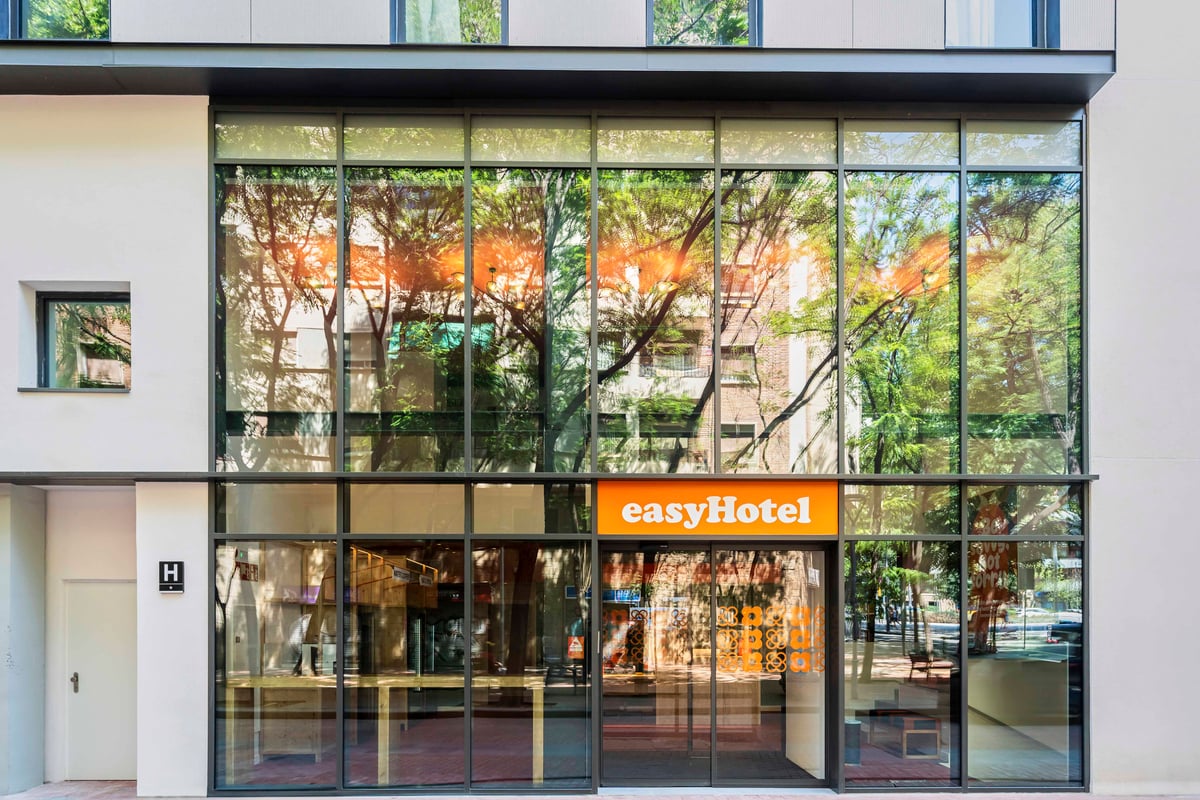 easyHotel Barcelona La Sagrera exterior with large glass windows reflecting trees and buildings.
