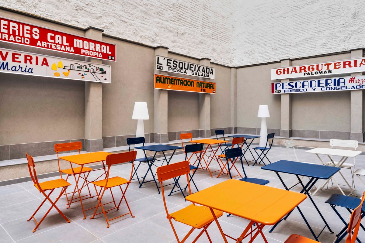 Outdoor seating area with colorful tables and chairs in a courtyard, Barcelona.