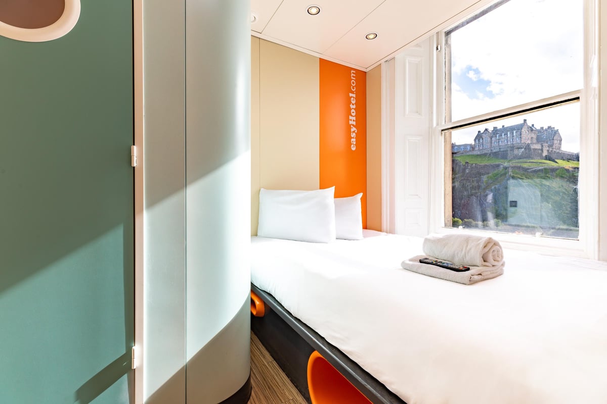 easyHotel Edinburgh double room featuring a bed, white bedding, and a window view of Edinburgh Castle.