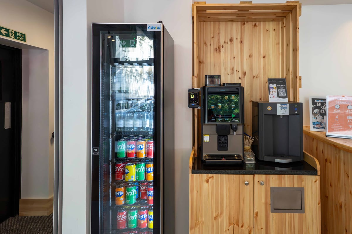 EasyHotel London Paddington reception area featuring a refrigerated display case with soft drinks and a coffee/water machine.