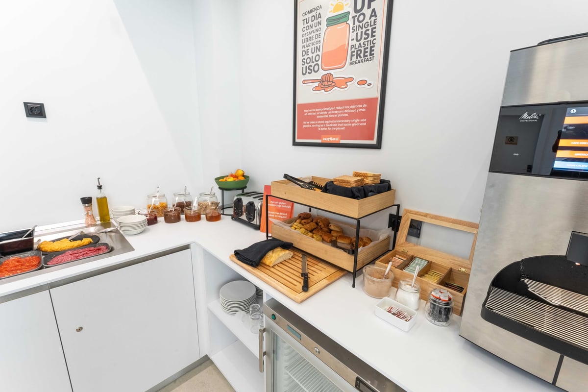 EasyHotel Madrid Alcalá restaurant breakfast buffet with pastries, bread, fruit, and condiments.