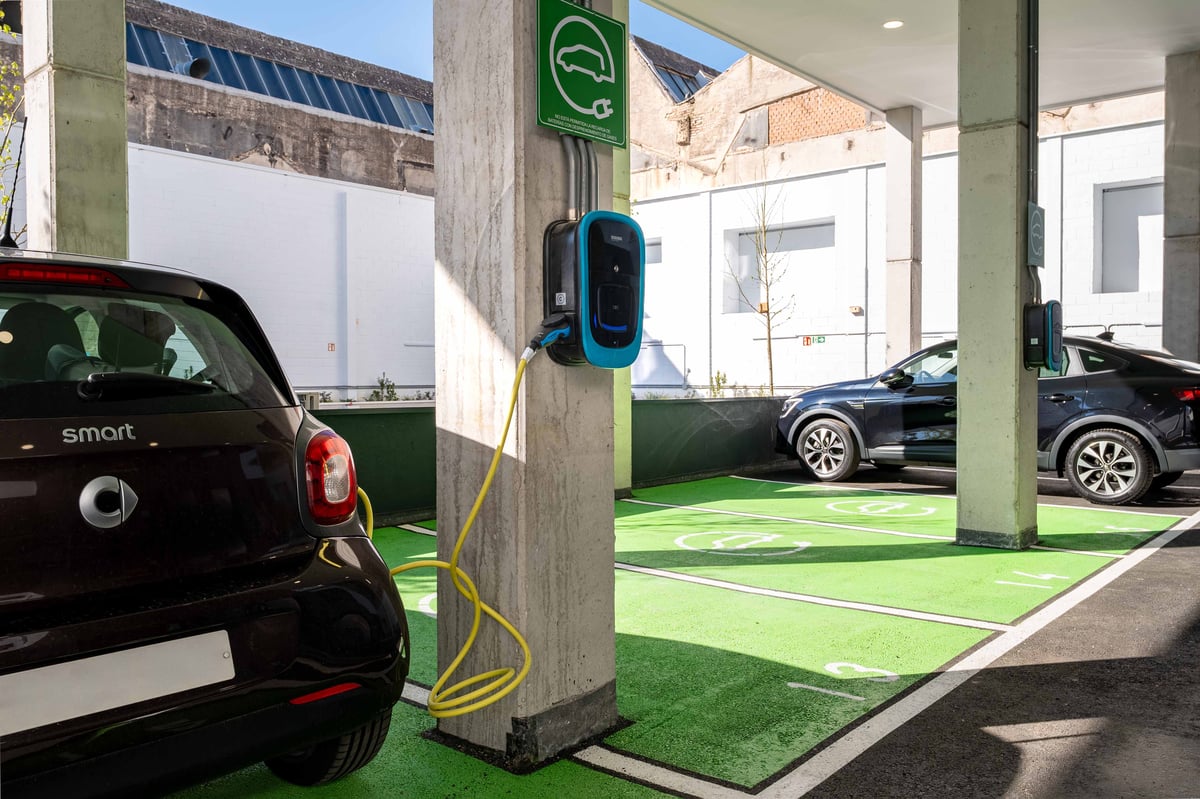An electric Smart car charging at a designated e-charging station with green parking spots at easyHotel Madrid Alcalá.