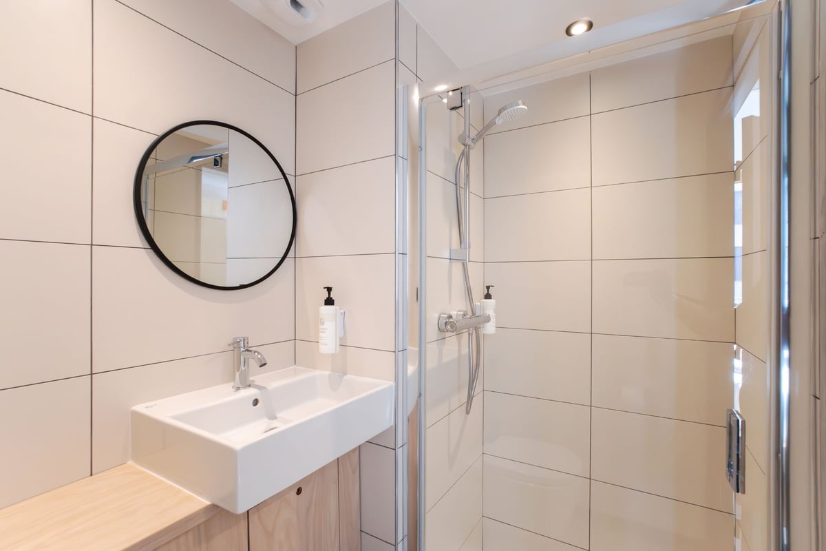 easyHotel Marseille Euromed modern bathroom with walk-in shower, basin, and round mirror.