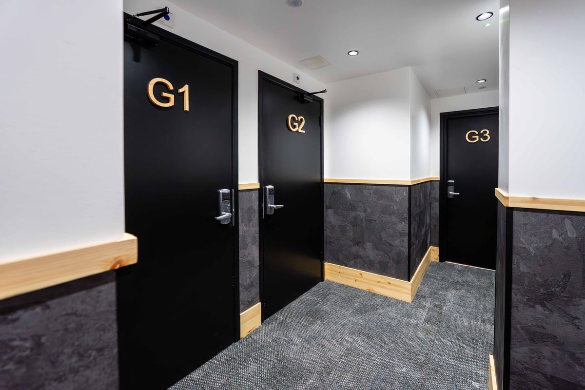 EasyHotel Paddington corridor with black doors labeled G1, G2, and G3. Gray carpet and dark wood accents.