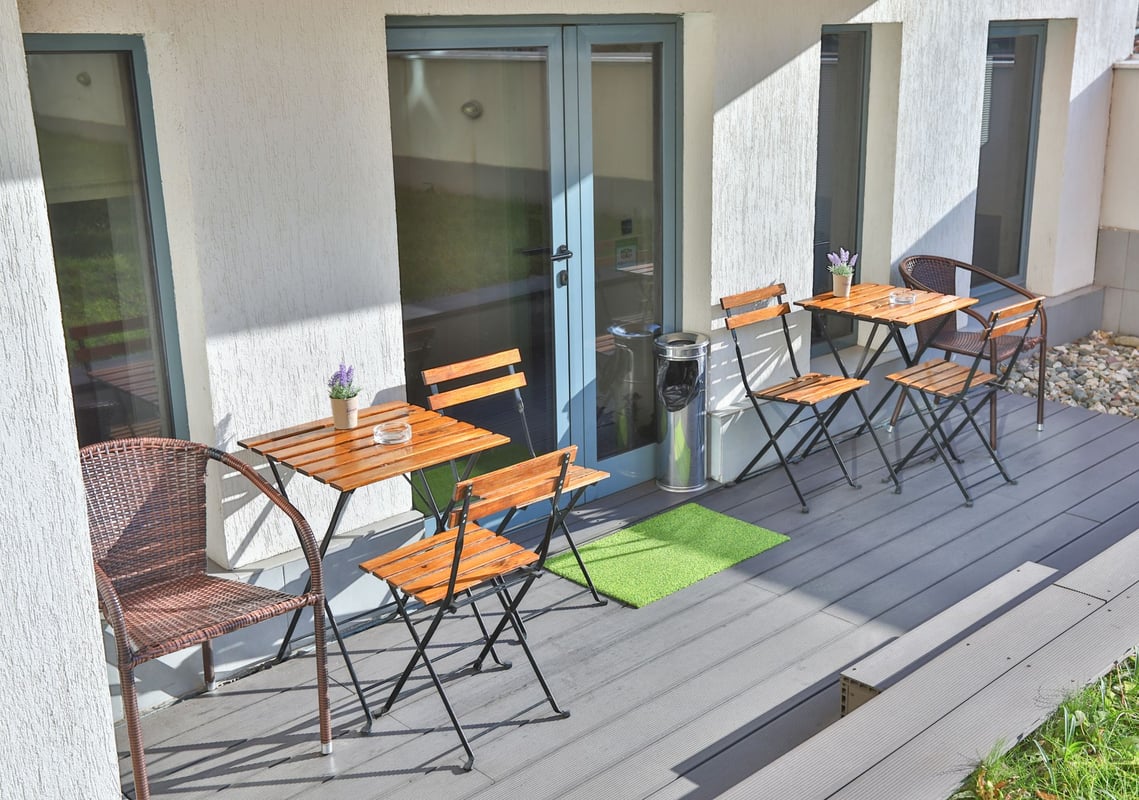 easyHotel Sofia outdoor terrace with wooden tables and chairs on grey composite decking, offering a bright al fresco seating area.