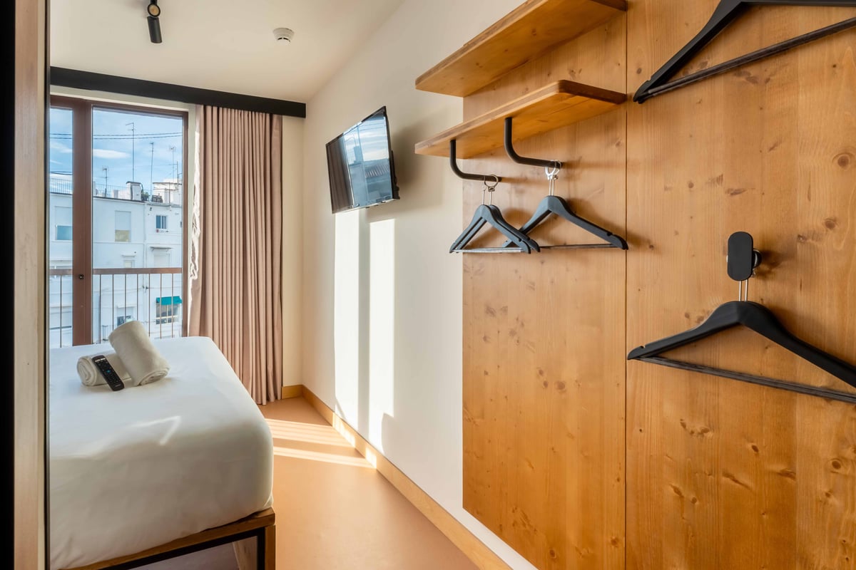 EasyHotel Valencia Ciutat Vella double room with bed, hangers, and wall-mounted TV.