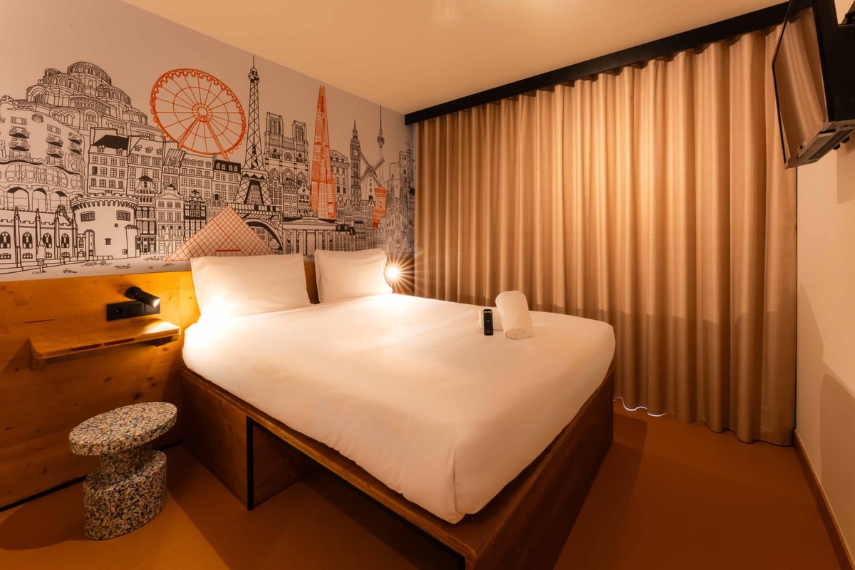 EasyHotel Valencia Ciutat Vella double room with a double bed, white linens, and a city-themed mural on the wall.