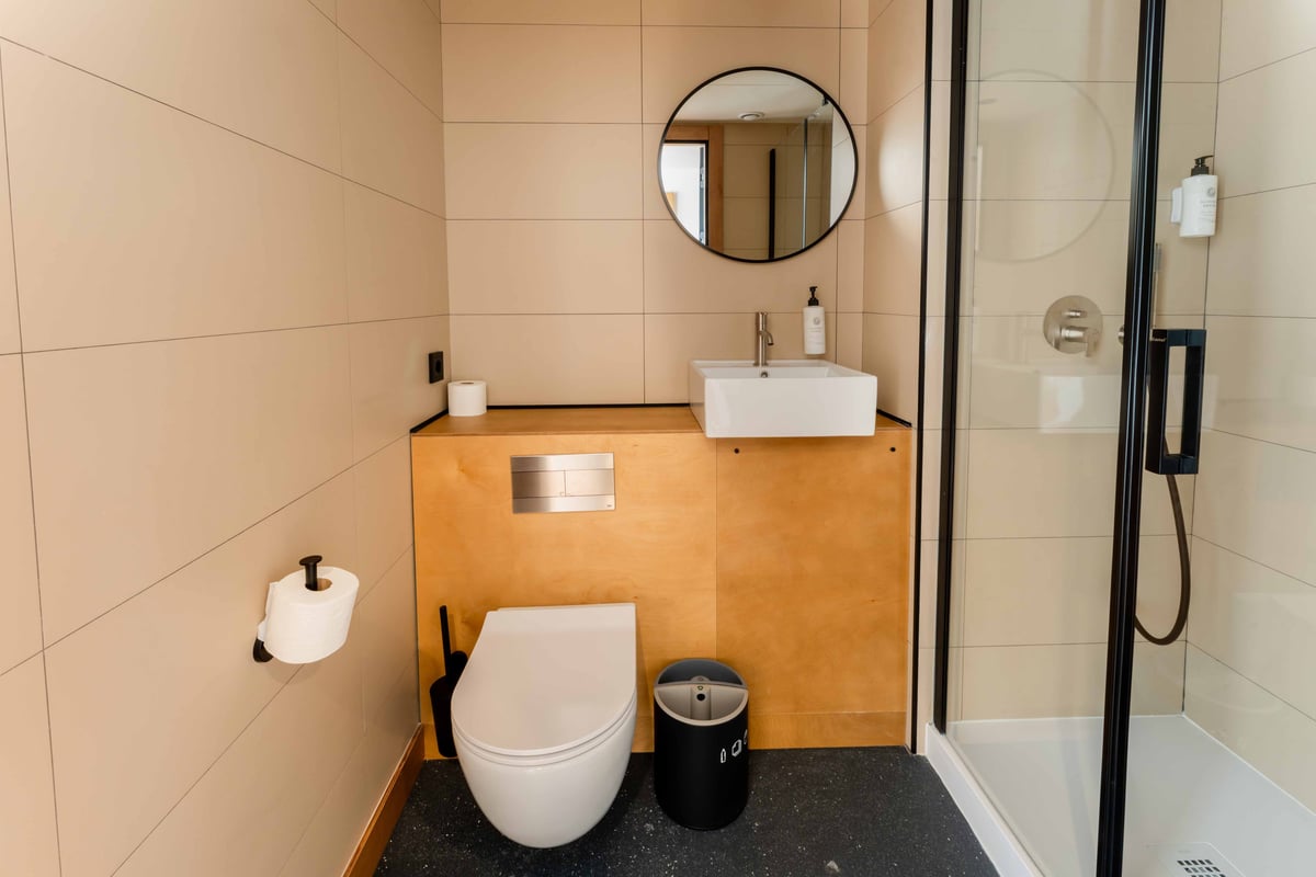 EasyHotel Valencia Ciutat Vella bathroom with toilet, sink, mirror, and shower.