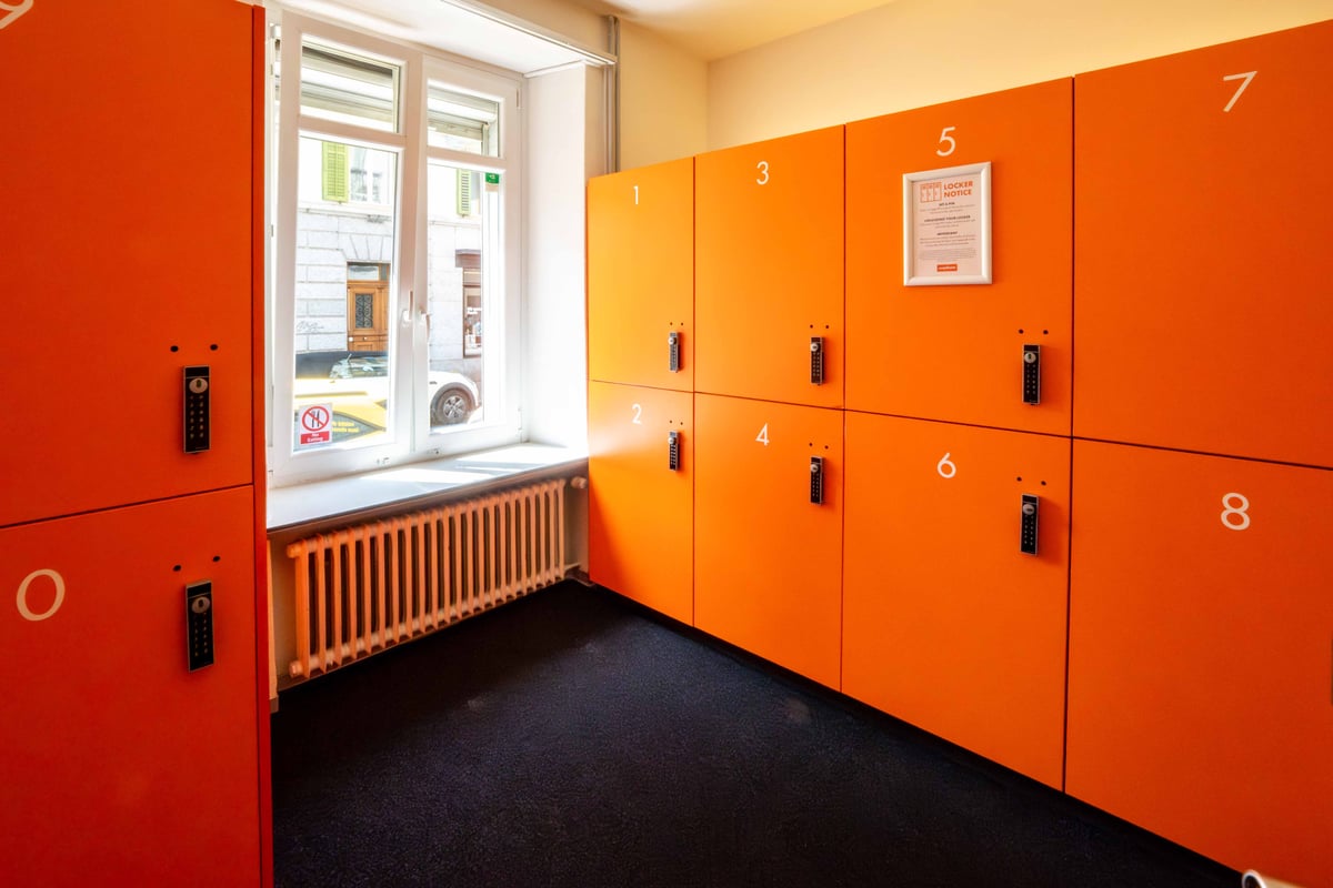 Orange lockers in an easyHotel room with a window, radiator, and black carpet.