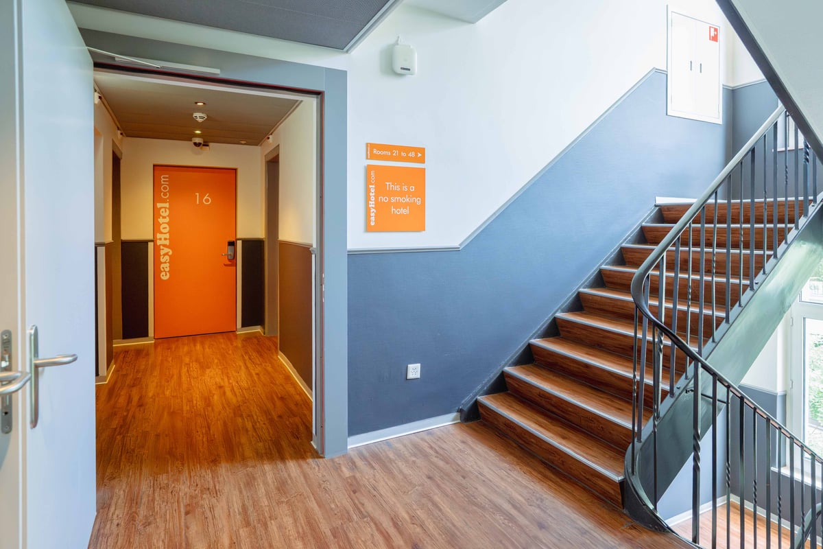 Staircase in an easyHotel Zurich City Centre with wooden steps and black railing.