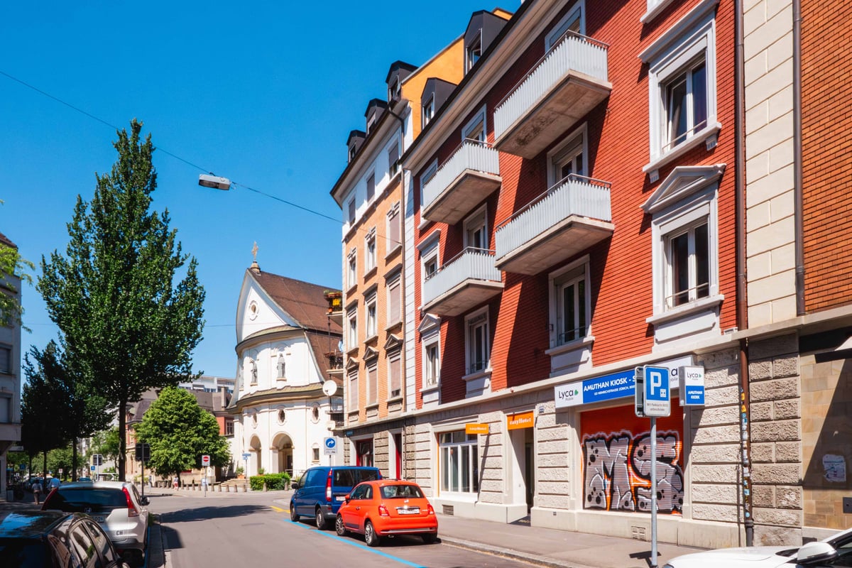 EasyHotel Zurich Limmatplatz exterior, showing a street view with the hotel building and surrounding buildings under a clear blue sky.