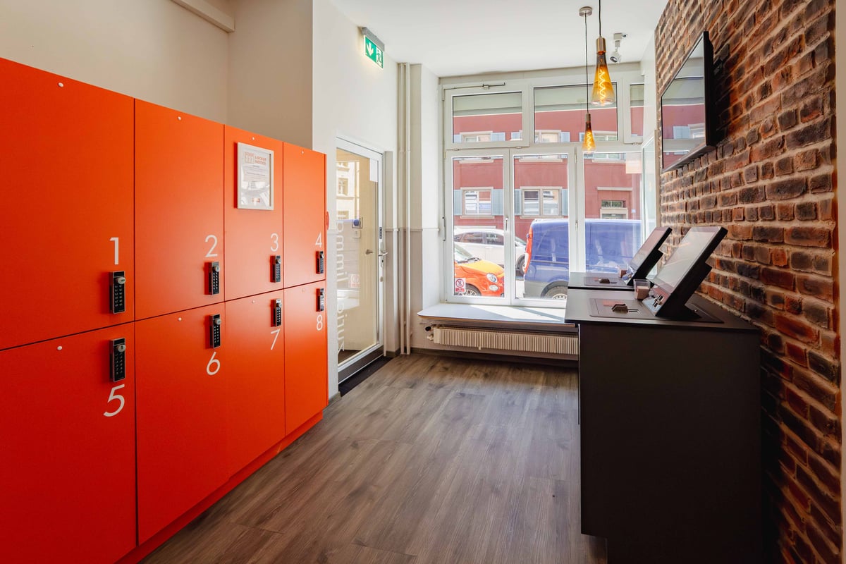 EasyHotel Zurich Limmatplatz reception area with orange lockers, a reception desk, and a window with street view.