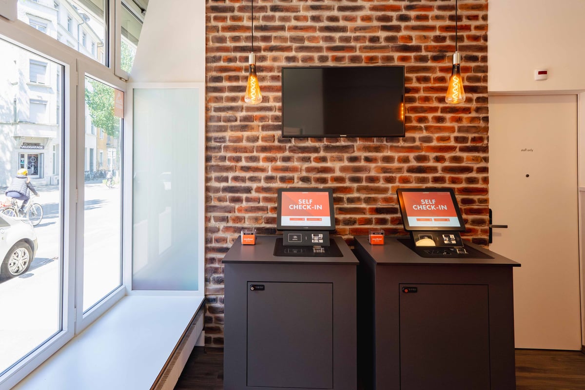 EasyHotel Zurich Limmatplatz reception area with self-check-in kiosks and brick wall.