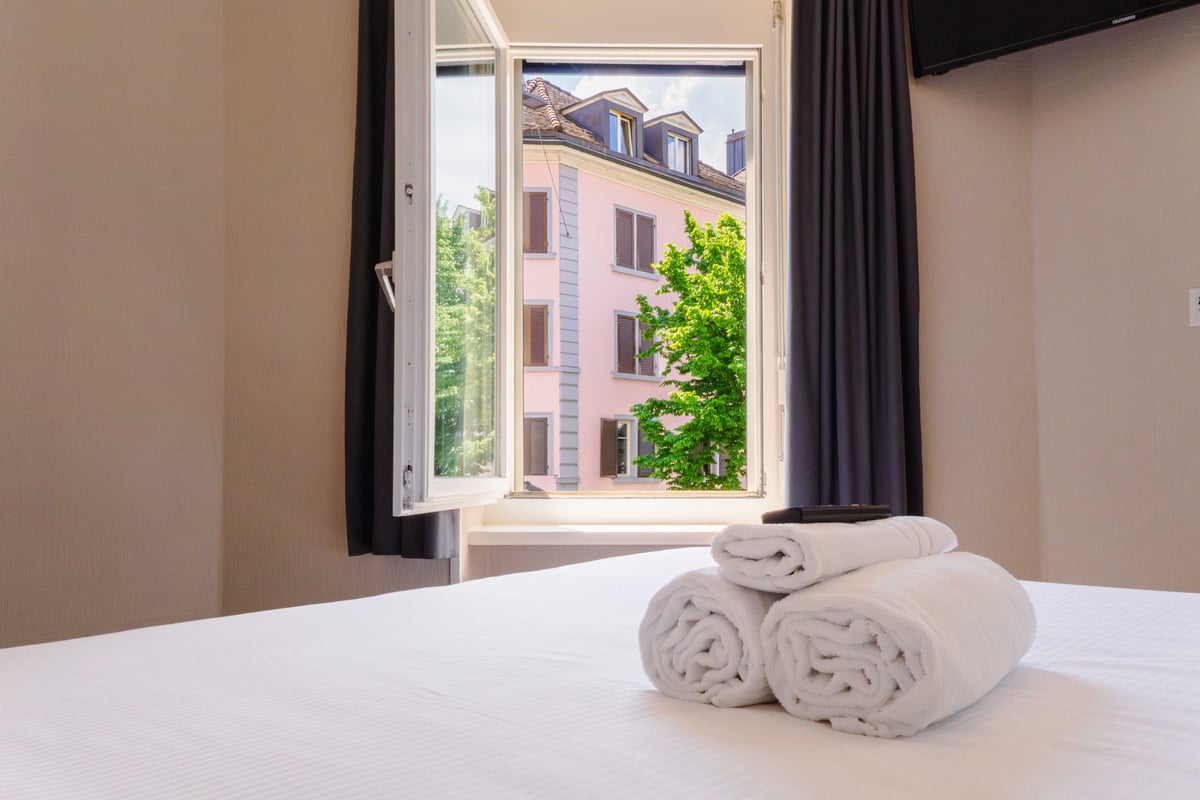 EasyHotel Zurich Main Station double room with a view of a pink building and trees.