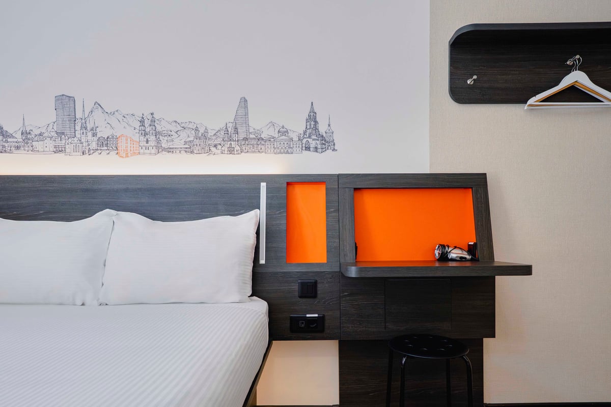 EasyHotel Zurich Main Station double room with bed, desk, and city skyline wall decal.