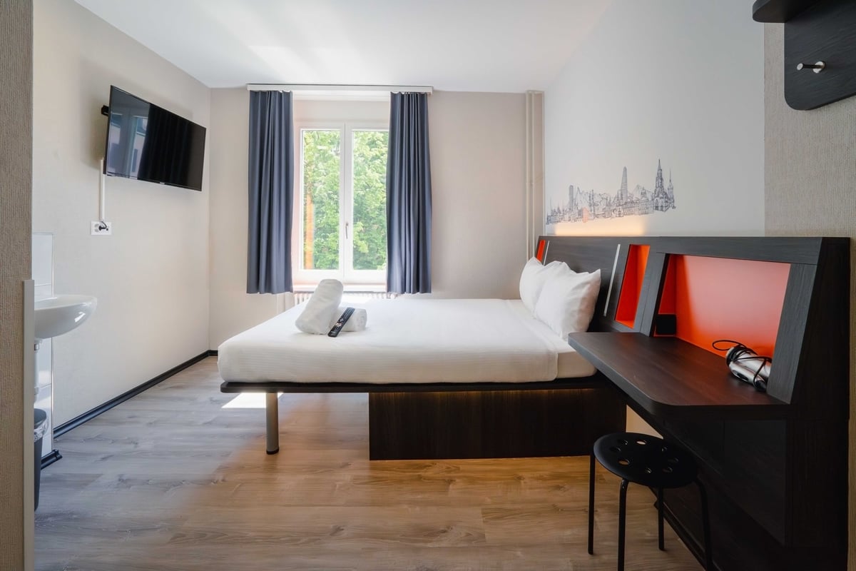 EasyHotel Zurich Main Station double room with a double bed, bedside table, desk, and television.