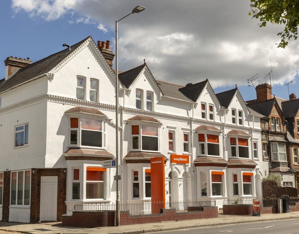 easyHotel Reading exterior: white terraced building with prominent orange window blinds and signage, viewed from the street on a sunny day.