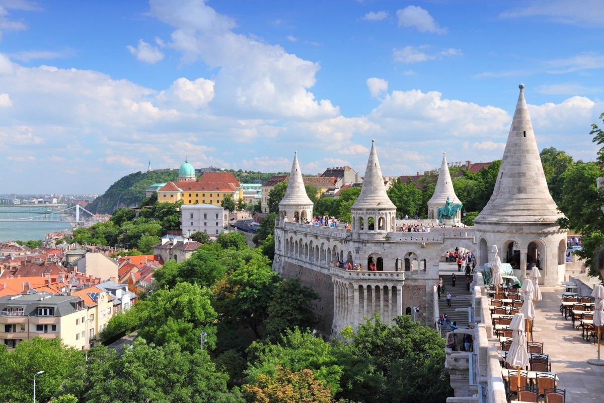 Fisherman's Bastion in Budapest, Hungary, showcasing its white neo-Romanesque towers and arches overlooking the city, Danube River, and Buda Castle under a blue sky.