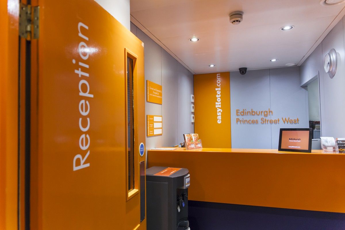 Bright orange and grey easyHotel Edinburgh Princes Street West reception area with a modern desk and signage.