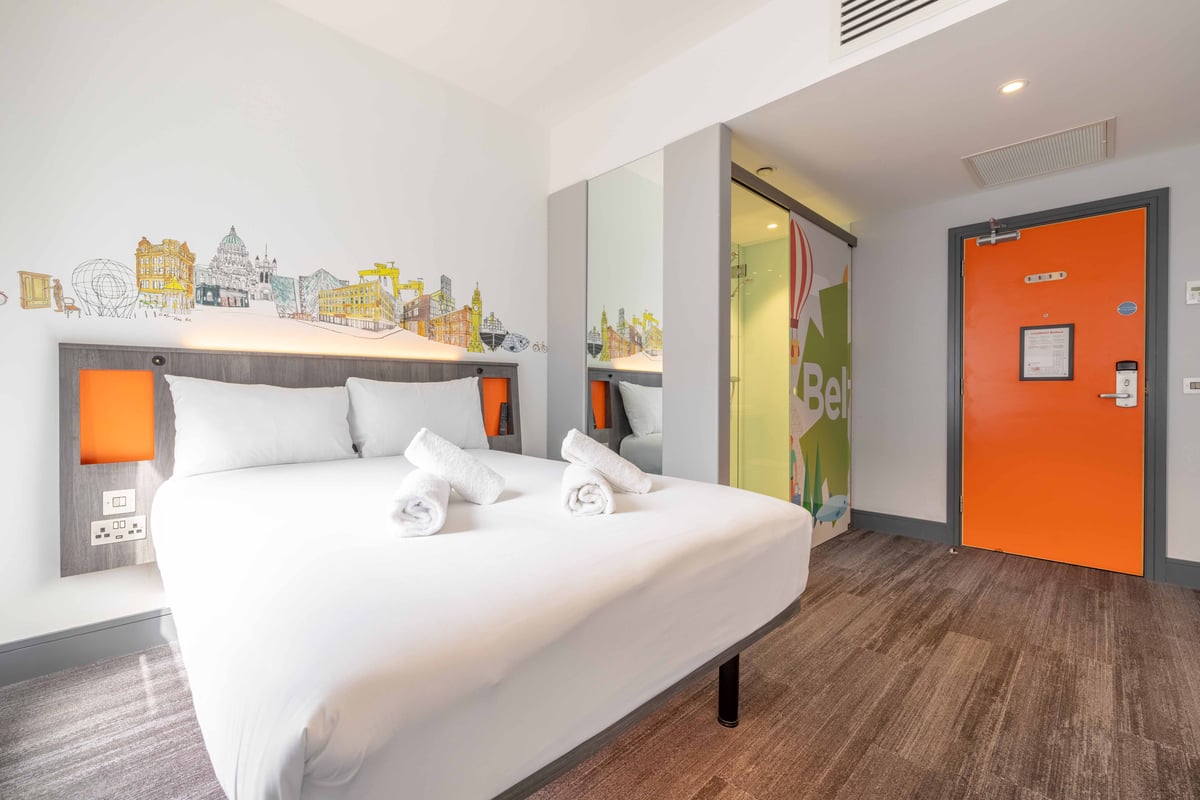 Superior double room with neatly made bed, folded towels, and illustrated cityscape headboard.