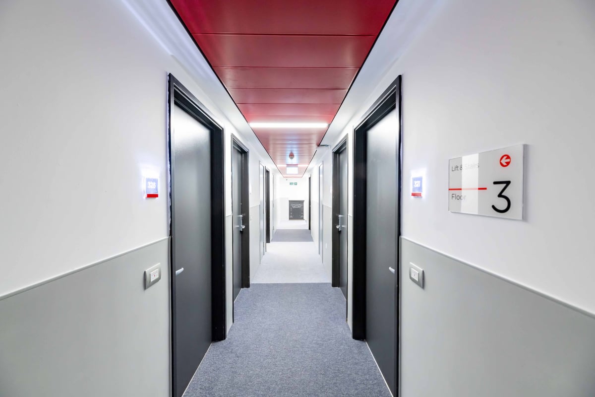 Hotel hallway on floor 3 with room doors on both sides and red ceiling panels.