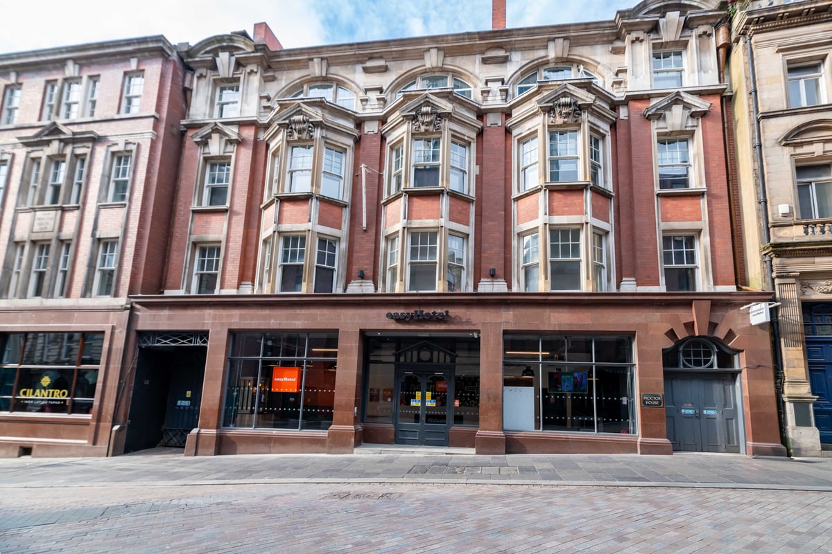 Exterior of easyHotel in a historic red-brick building with bay windows.