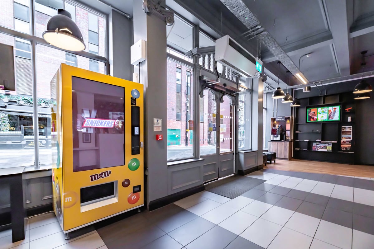 Hotel entrance area with yellow vending machine and large windows.