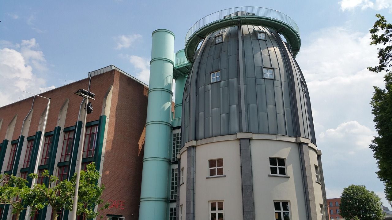 Exterior view of the Bonnefanten Museum in Maastricht, Netherlands, featuring its distinctive lead-clad cupola, light blue cylindrical staircase, and red brick facade.