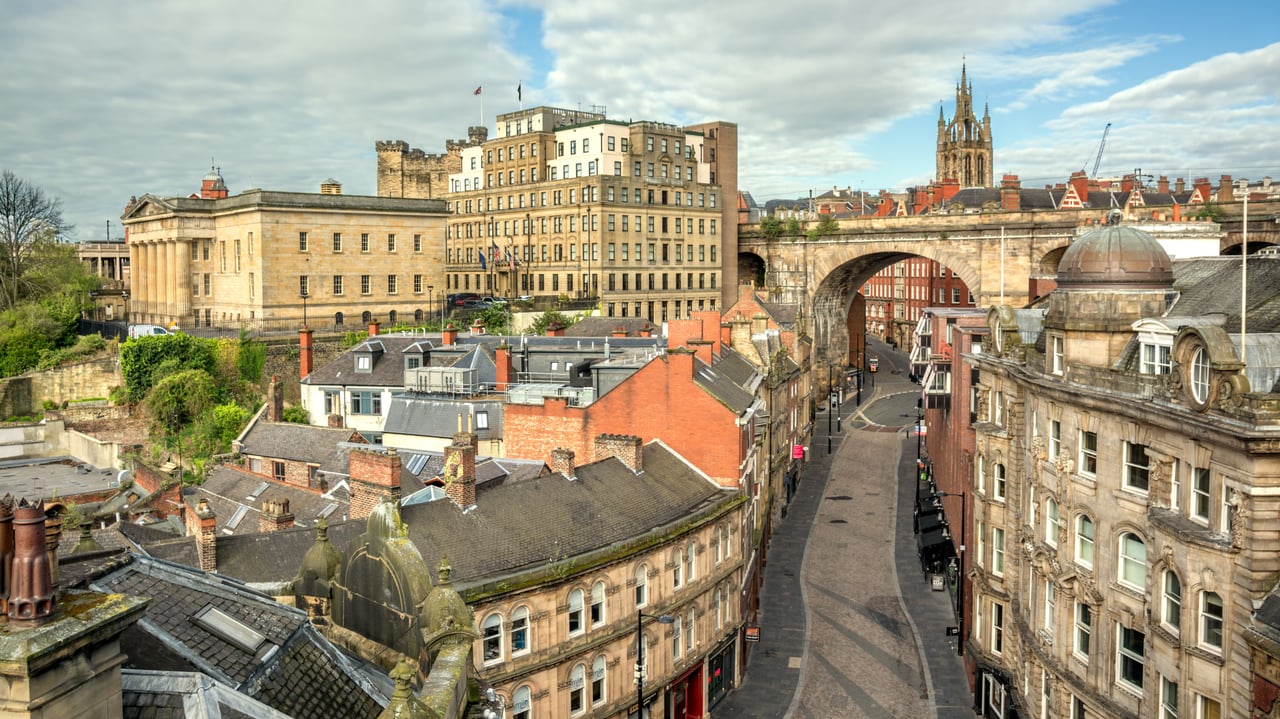 Panoramic view of Newcastle upon Tyne, UK, featuring the historic High Level Bridge, St. Nicholas Cathedral, and traditional city architecture.
