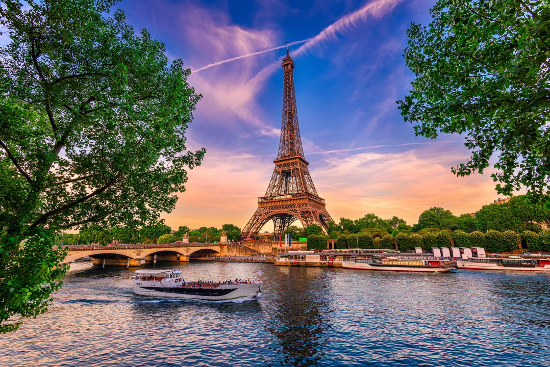 Eiffel Tower and Seine River at sunset in Paris, France, with a boat on the water.